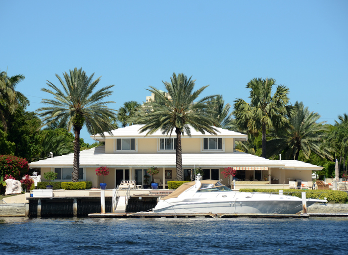 a big waterfront home with a yacht in the dock