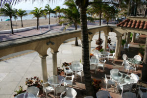 "Outdoor restaurant amongst palm trees with view of beach and ocean in Fort Lauderdale, Florida."