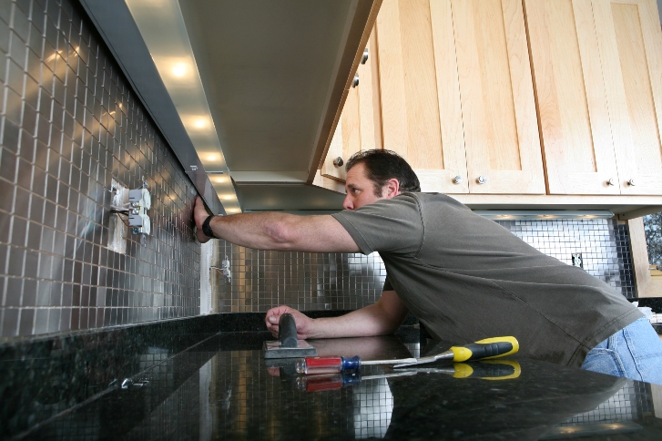 man fixing the kitchen tiles
